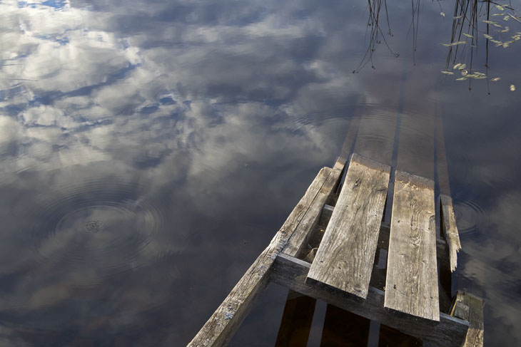 Steg und Spiegelung von Wolken im Wasser